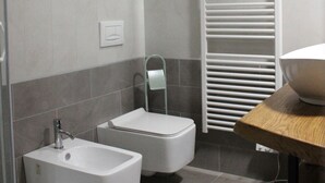 Une salle de bain moderne équipée d’un bidet, de toilettes et d’un porte-serviettes.