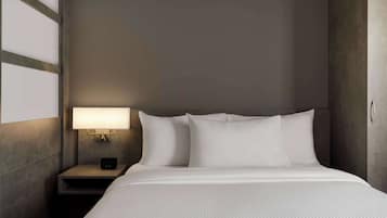 A neatly made bed with white linens in a hotel room.