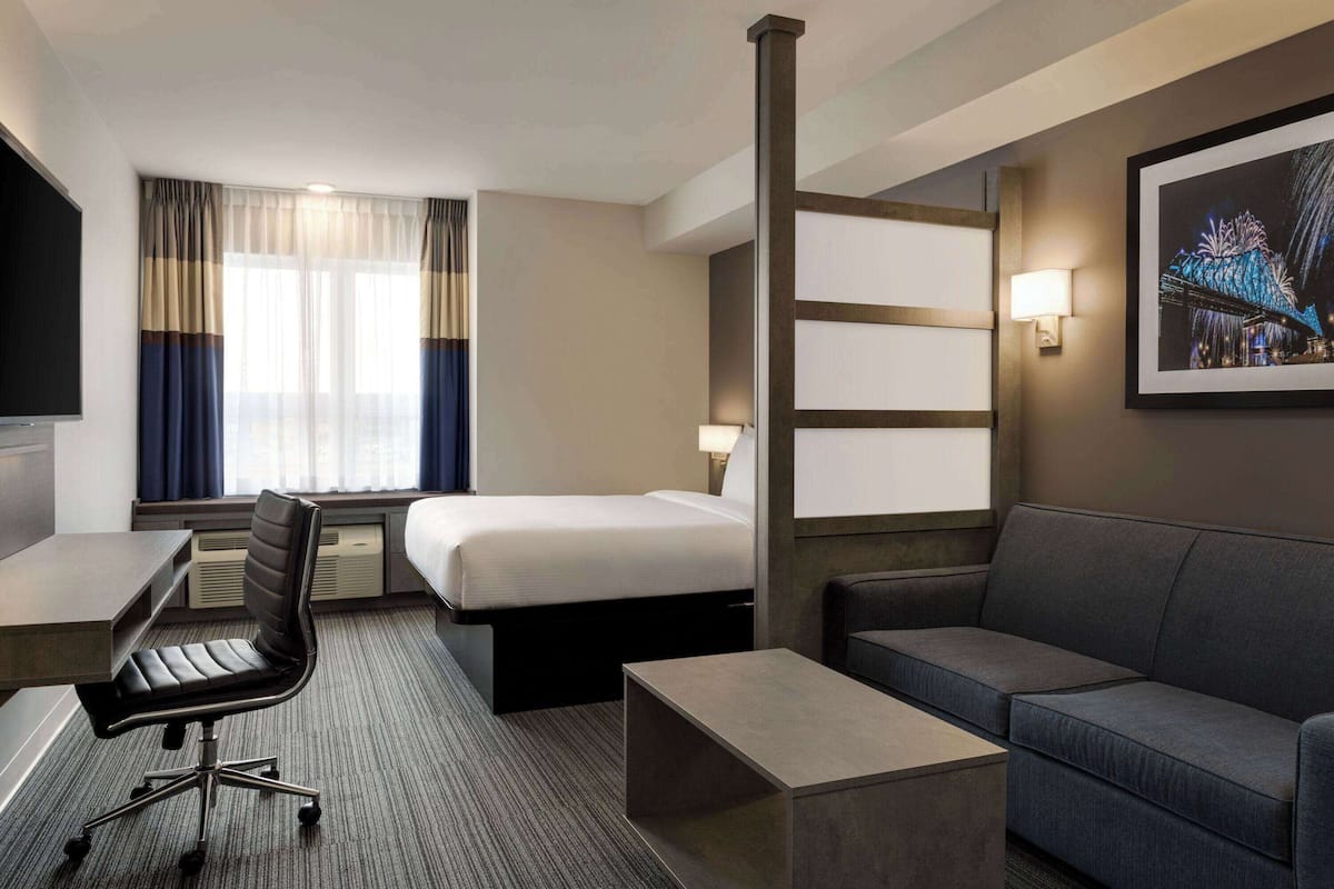 Une chambre d’hôtel équipée d’un lit, d’un bureau, d’une chaise, d’un canapé et d’une télévision.