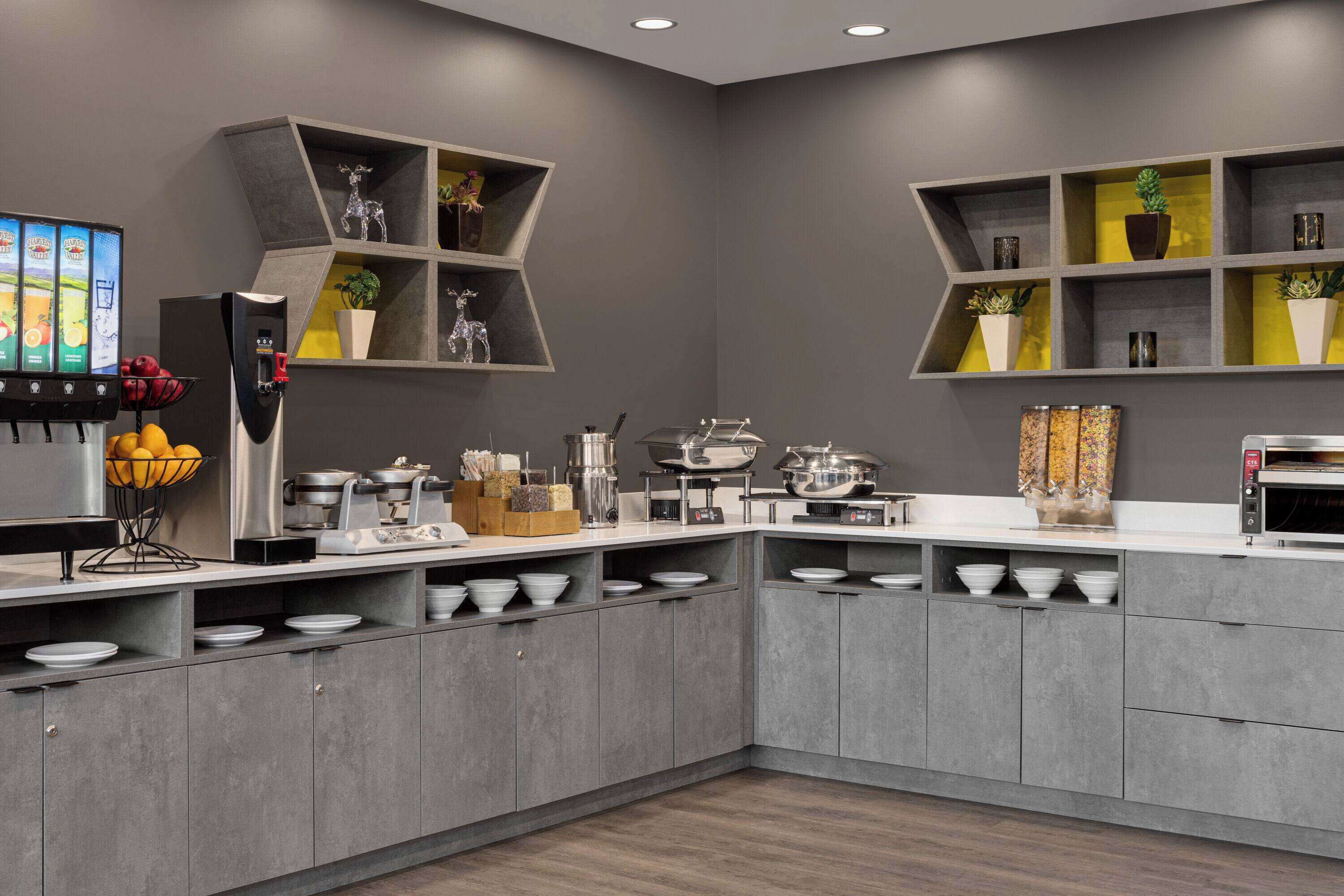 A modern kitchen with grey cabinets, a built-in microwave, and a fruit bowl.