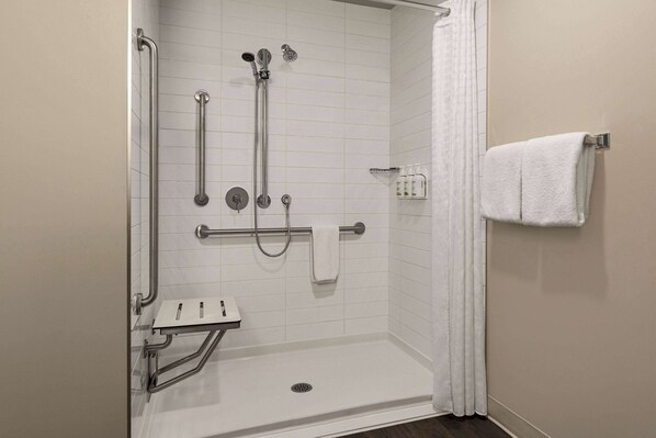 A wheelchair-accessible shower with grab bars, a handheld showerhead, and a handheld faucet.