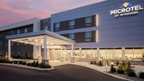 A modern Microtel hotel by Wyndham with a covered entrance, stone accents, and a well-lit facade.