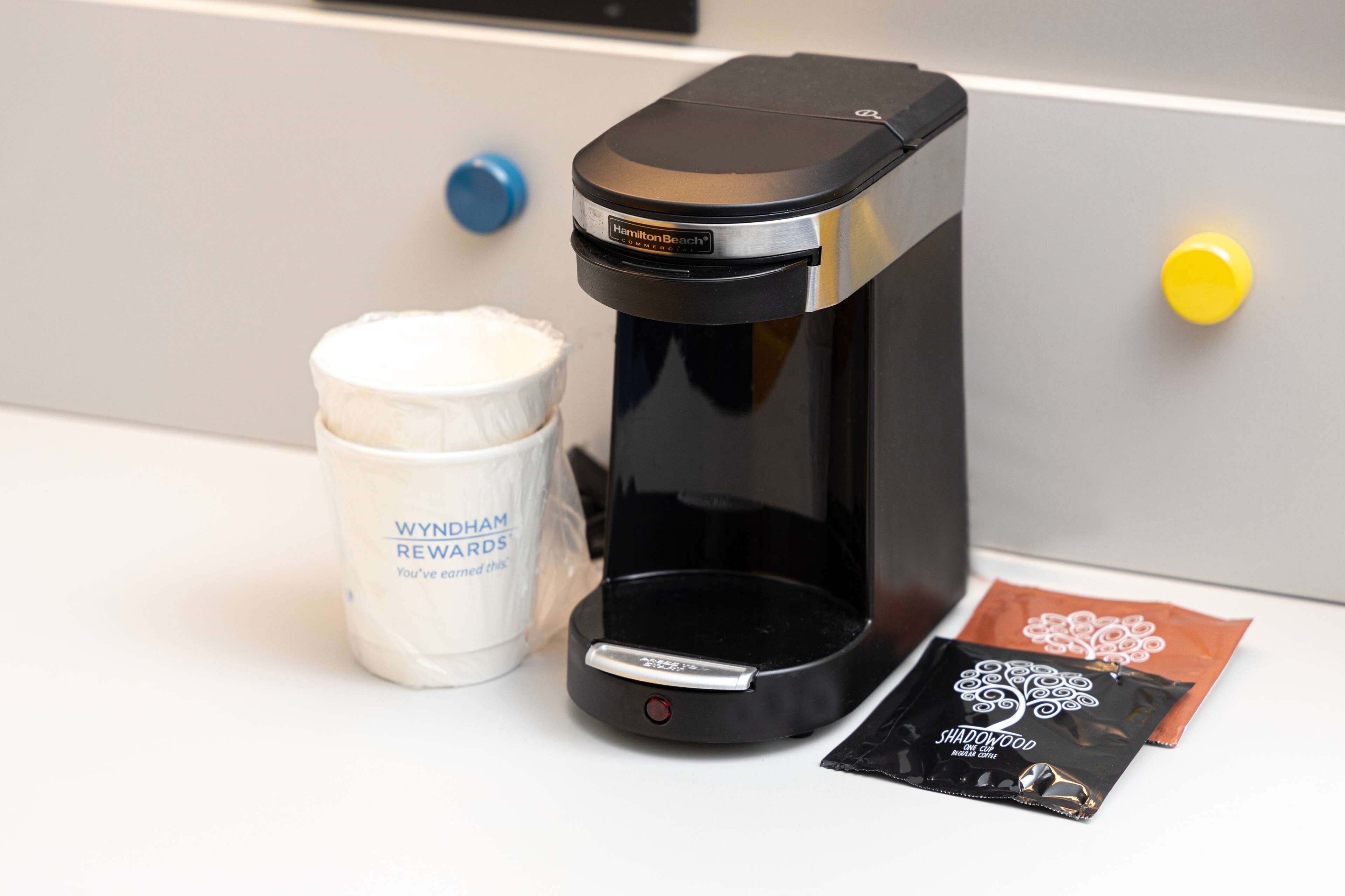 A coffee maker, a container labeled "WYNHAM REWARDS," and two packets of coffee.