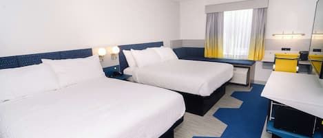 Habitación de hotel con dos camas, un escritorio, una silla, un televisor y una ventana con cortinas.