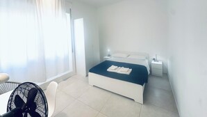A hotel room with a bed, bedside tables, a chair, and a fan. - Fantastic Apartment in Historic Center - Palermo (Palermo)