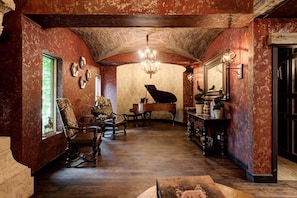 Une pièce avec un grand piano, un lustre et un grand miroir.