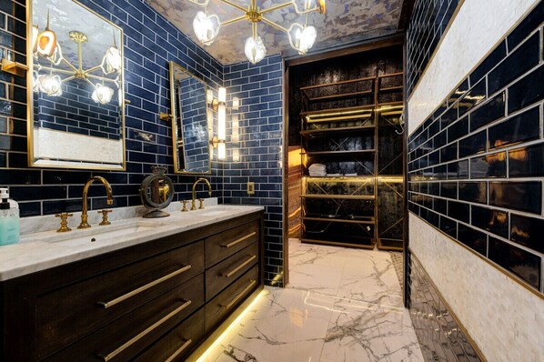 A modern bathroom with a large mirror, dual sinks, and a vanity with drawers.