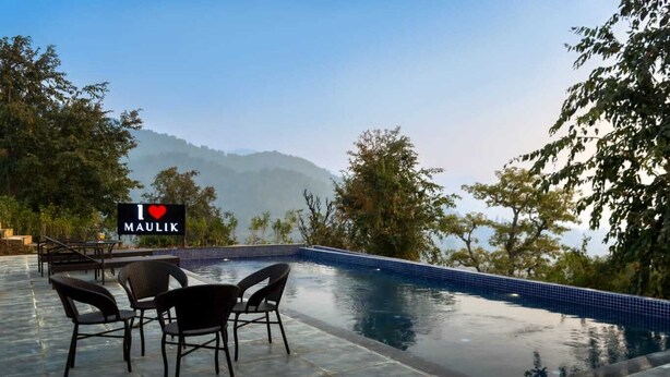 An infinity pool with a view of mountains and trees, surrounded by outdoor furniture. - MAULIK RETREAT (Ramnagar)