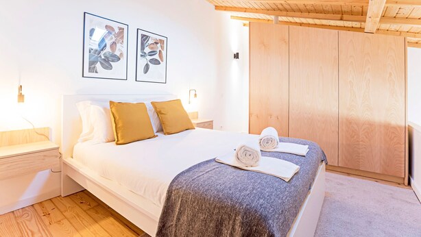 Ein Schlafzimmer mit einem großen Bett, einem Holz-Kopfteil, zwei gerahmten Bildern an der Wand und einem Holzschrank.