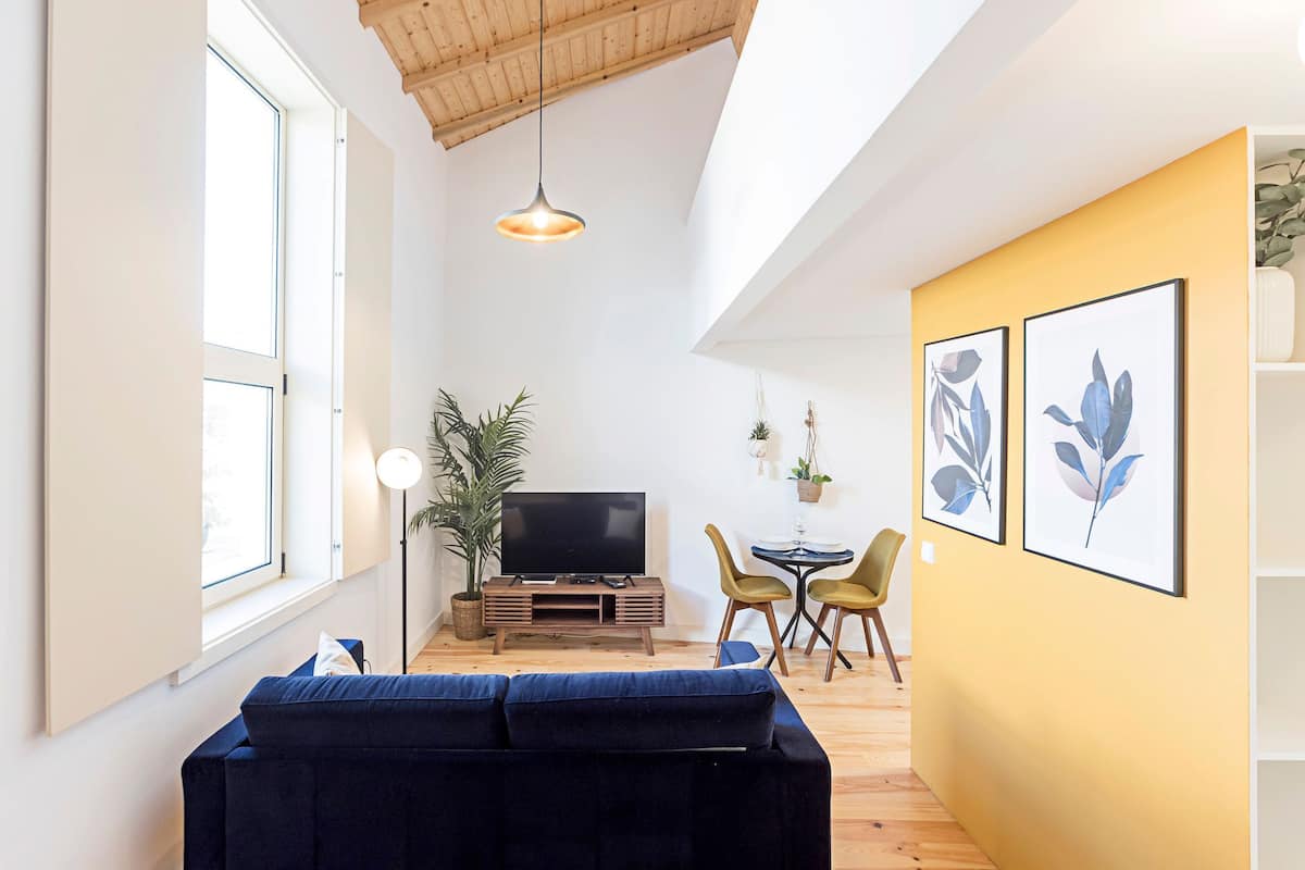 A living room with a sofa, TV, and a dining area with chairs and a table.