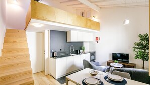 Eine moderne Küche mit weißen Schränken, einem eingebauten Ofen und einem Essbereich mit Tisch für zwei Personen.