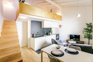 A modern kitchen with white cabinets, a built-in oven, and a dining area with a table set for two.