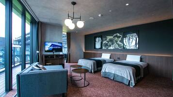 Quarto de hotel moderno com duas camas, um sofá, uma TV e uma janela grande com vista para a cidade.
