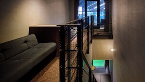 Een modern interieur met een bank, een trap en uitzicht op een buitenruimte.