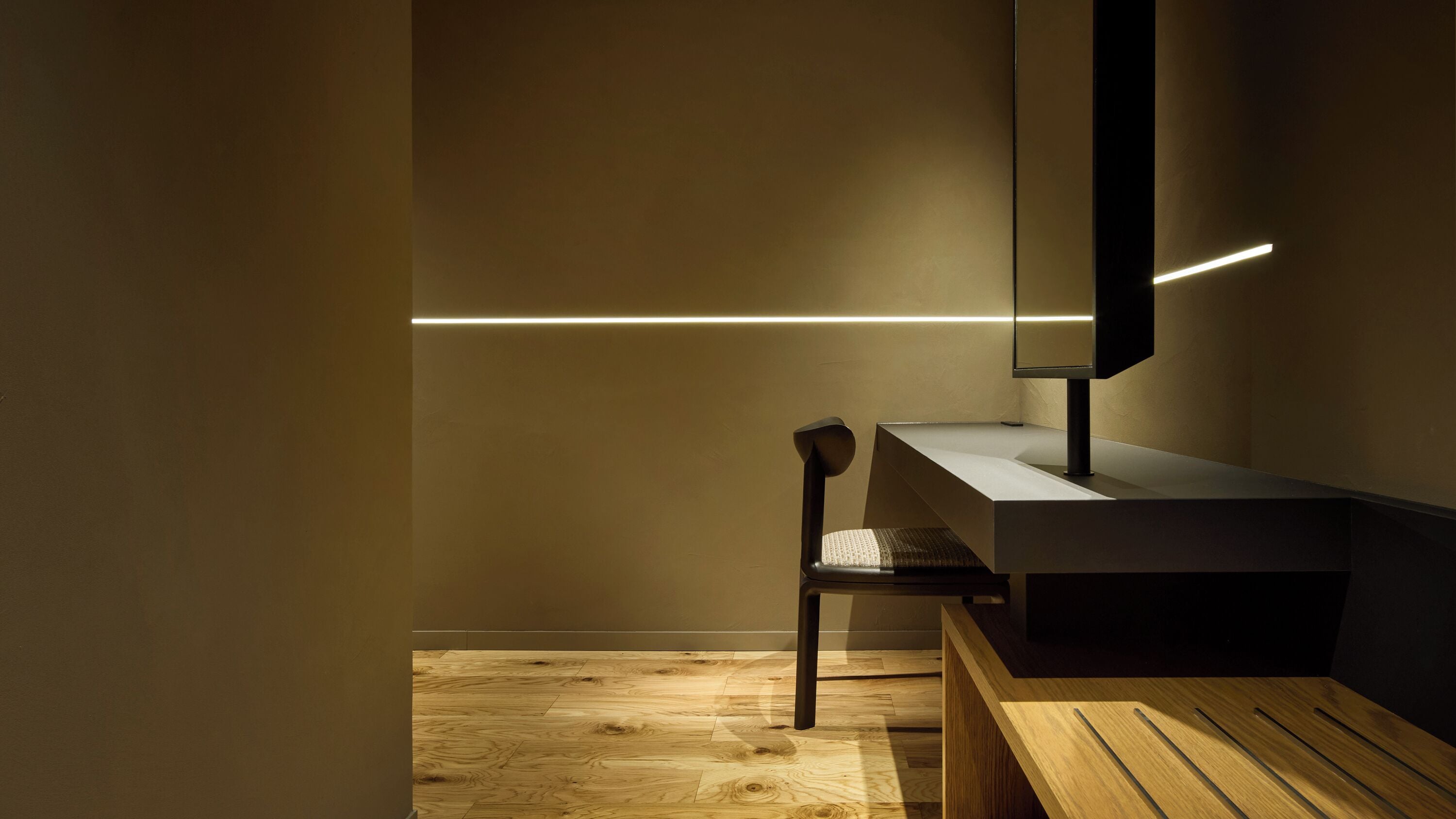 A modern bathroom with a wooden bench, a sink, and a mirror.