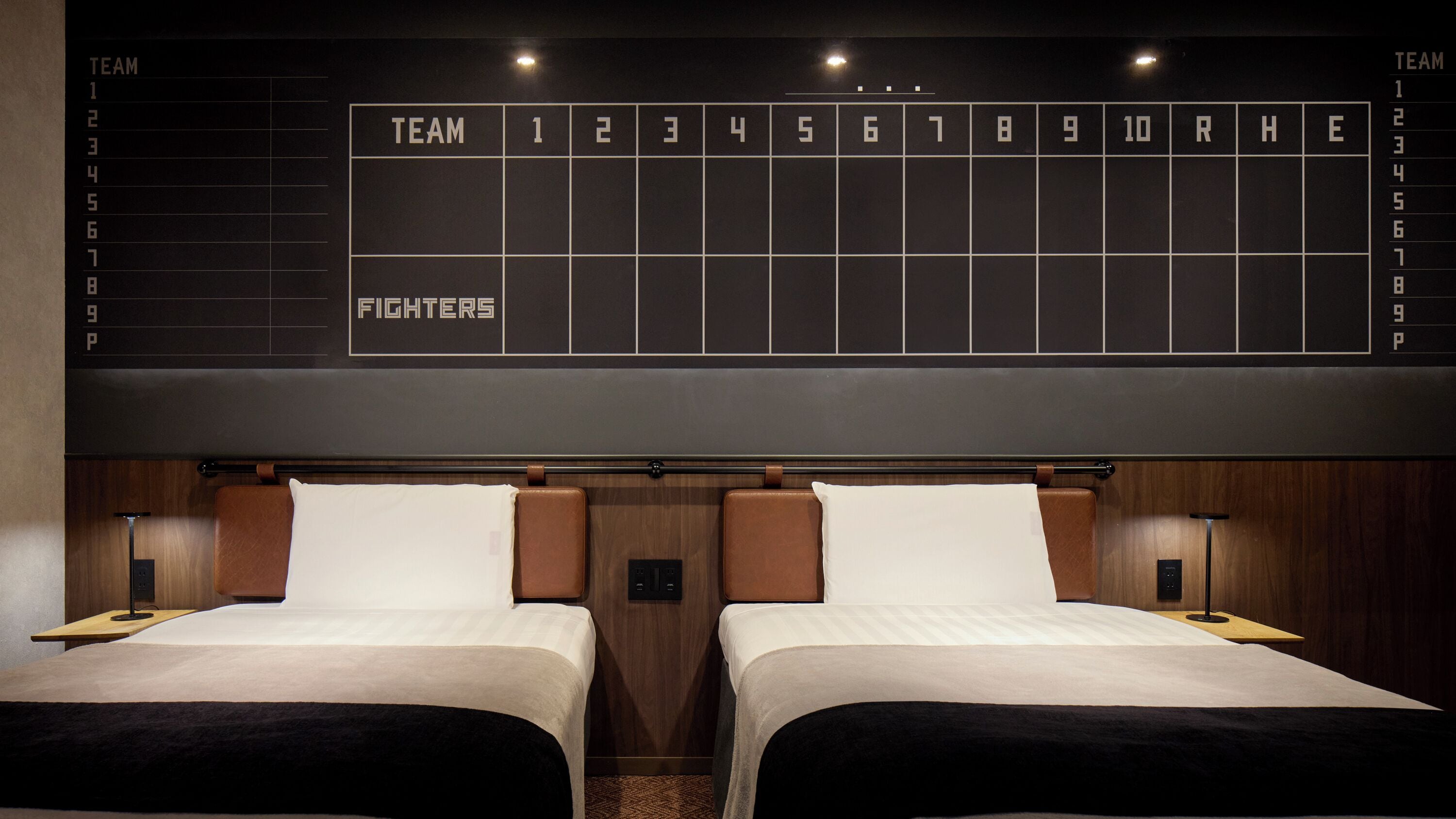 A hotel room with two beds, a large digital scoreboard, and a wooden headboard.