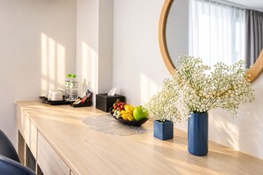 A hotel room with a wooden desk, a mirror, a fruit bowl, a tissue box, and a vase with flowers. - Moonlight Nha Trang Hotel (Nha Trang)