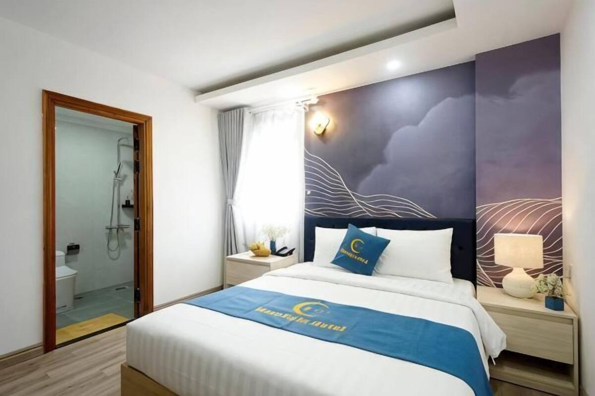 Ein Hotelzimmer mit Bett, Nachttisch, Lampe, Wand mit Wellendesign und Dusche.