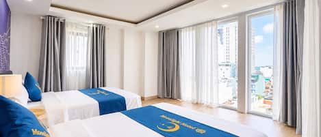 A hotel room with two beds, a city view, and a large window with curtains.