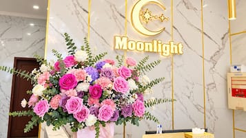 Una recepción de hotel con encimera de mármol, un arreglo floral y un letrero que dice 'Moonlight'.