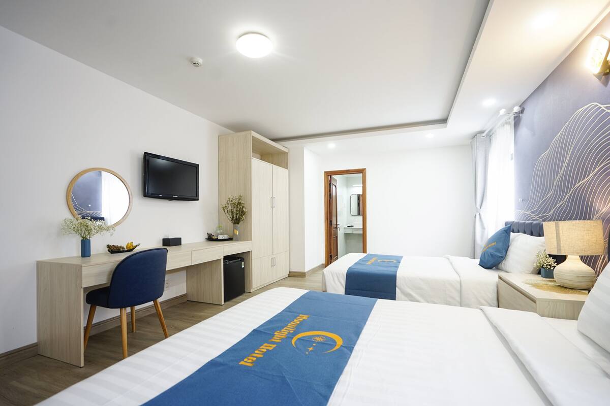 Ein Hotelzimmer mit zwei Betten, einem Schreibtisch, einem Fernseher und einem Badezimmer.
