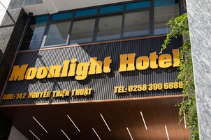 Un cartel de hotel con el nombre 'Moonlight Hotel' e información de contacto.