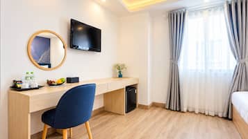 Una habitación de hotel con escritorio, silla, televisor y cama.