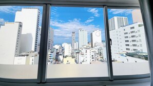 Vista desde una ventana de un paisaje urbano con varios edificios altos, incluyendo un hotel llamado "DONG FUONG HOTEL".