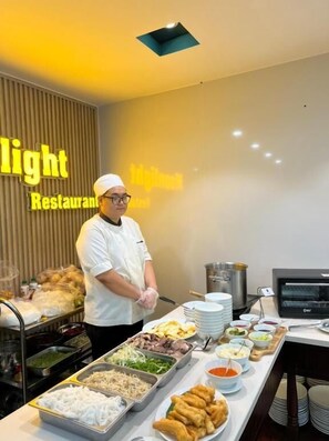 A buffet setup with various food items and a person in chef attire. - Moonlight Nha Trang Hotel (Nha Trang)