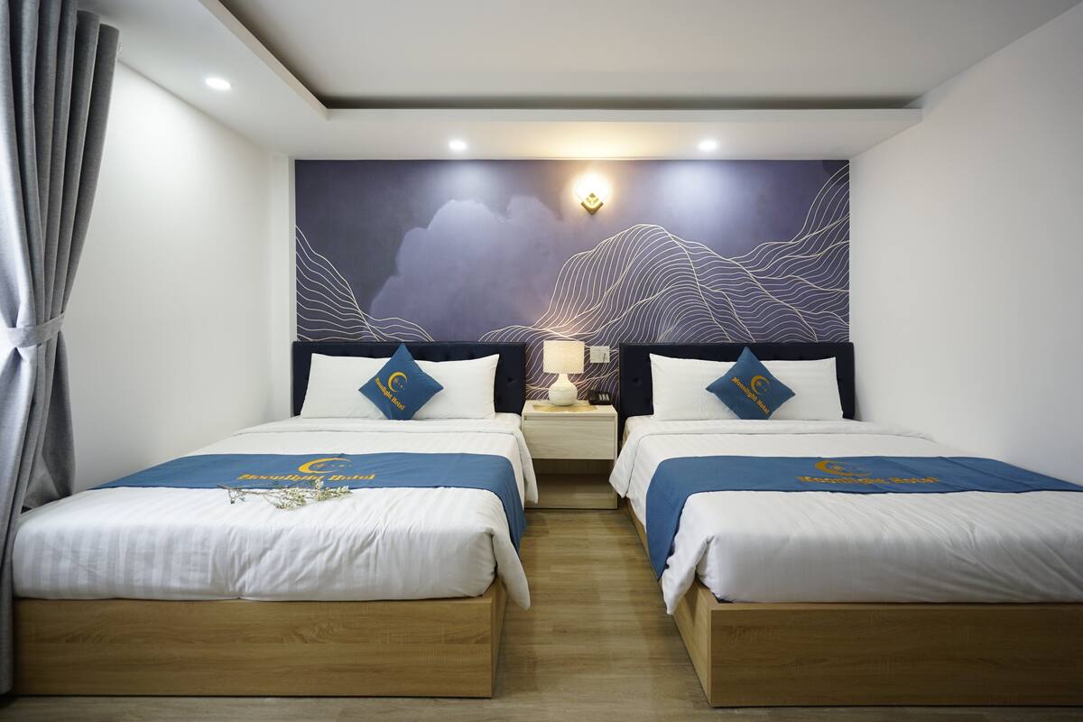 Ein Hotelzimmer mit zwei Betten, einem großen Wandbild und einem Nachttisch mit Lampe.
