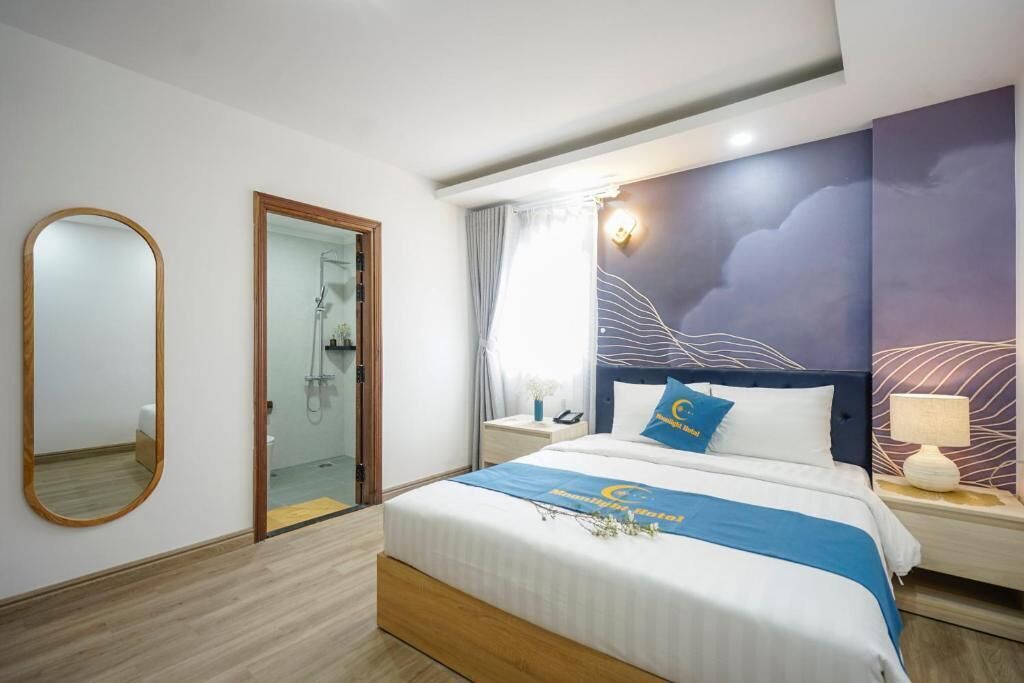 Quarto de hotel com cama, mesa de cabeceira, espelho, chuveiro e parede com padrão de ondas.
