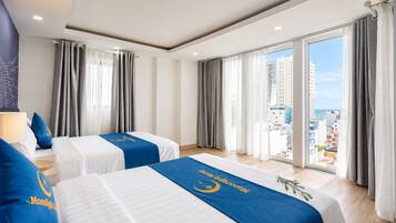 Habitación de hotel con dos camas, un ventanal con cortinas y vista a la ciudad.