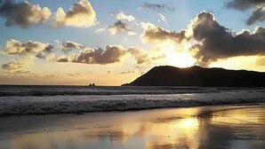 Ein Strand mit ruhigen Wellen und einem Sonnenuntergang.