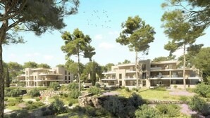 Ein moderner Wohnkomplex mit mehreren Gebäuden, umgeben von natürlicher Vegetation und Bäumen.