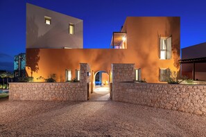 A modern building with a stone facade, a central archway, and a well-lit entrance.