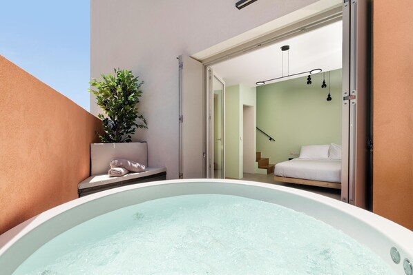 A hot tub in a room with a bed and a plant.
