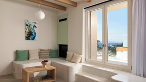 Una sala moderna con un sofá, una mesa de centro de madera, un cuadro y un ventanal con vistas.