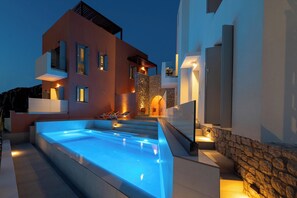 A modern building with a swimming pool, stone walls, and a well-lit exterior.