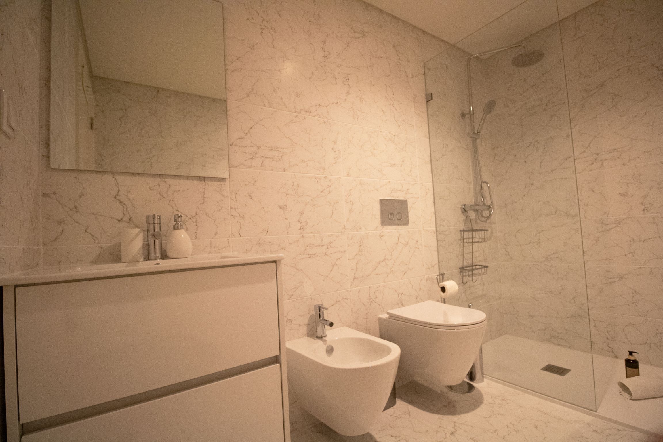 A modern bathroom with a bidet, toilet, and glass-enclosed shower.
