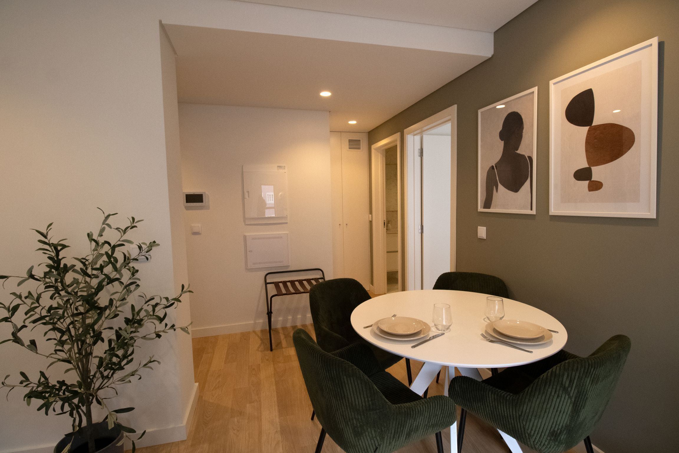 A dining area with a round table, four chairs, and a potted plant.