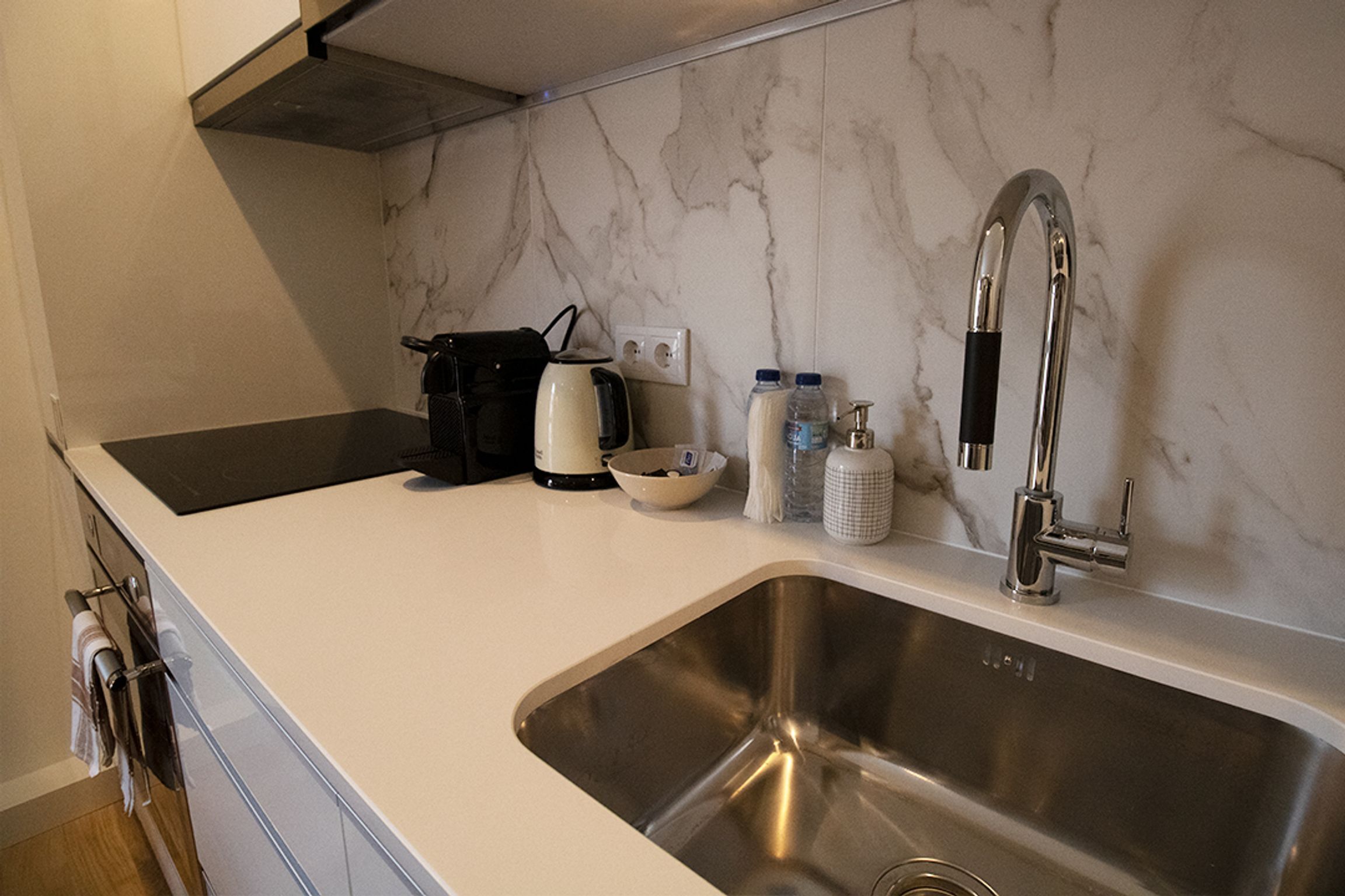 Una cocina moderna con un lavamanos de acero inoxidable, una cafetera y un hervidor sobre la encimera.