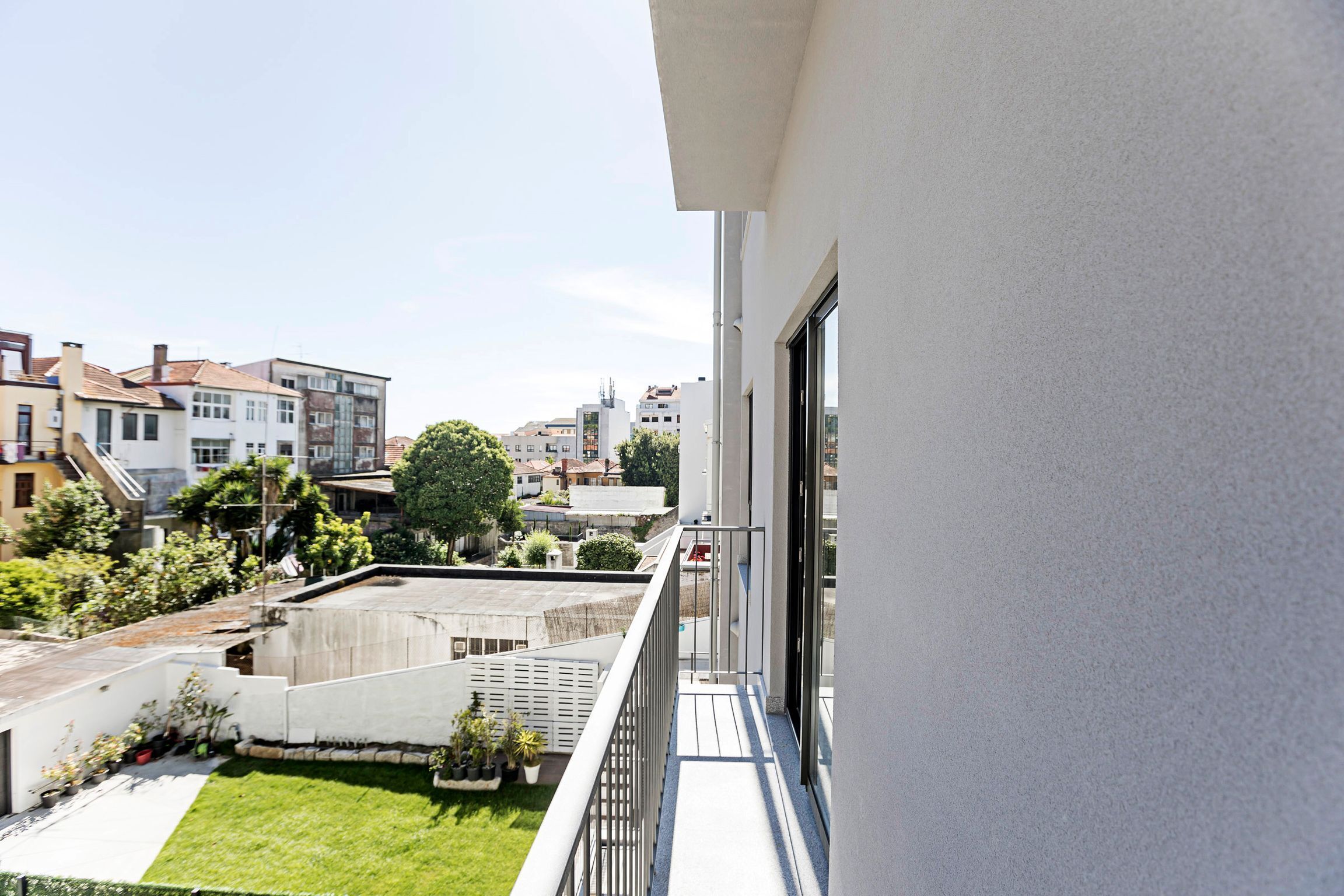 En balkon med udsigt over en grøn græsplæne og omkringliggende bygninger.