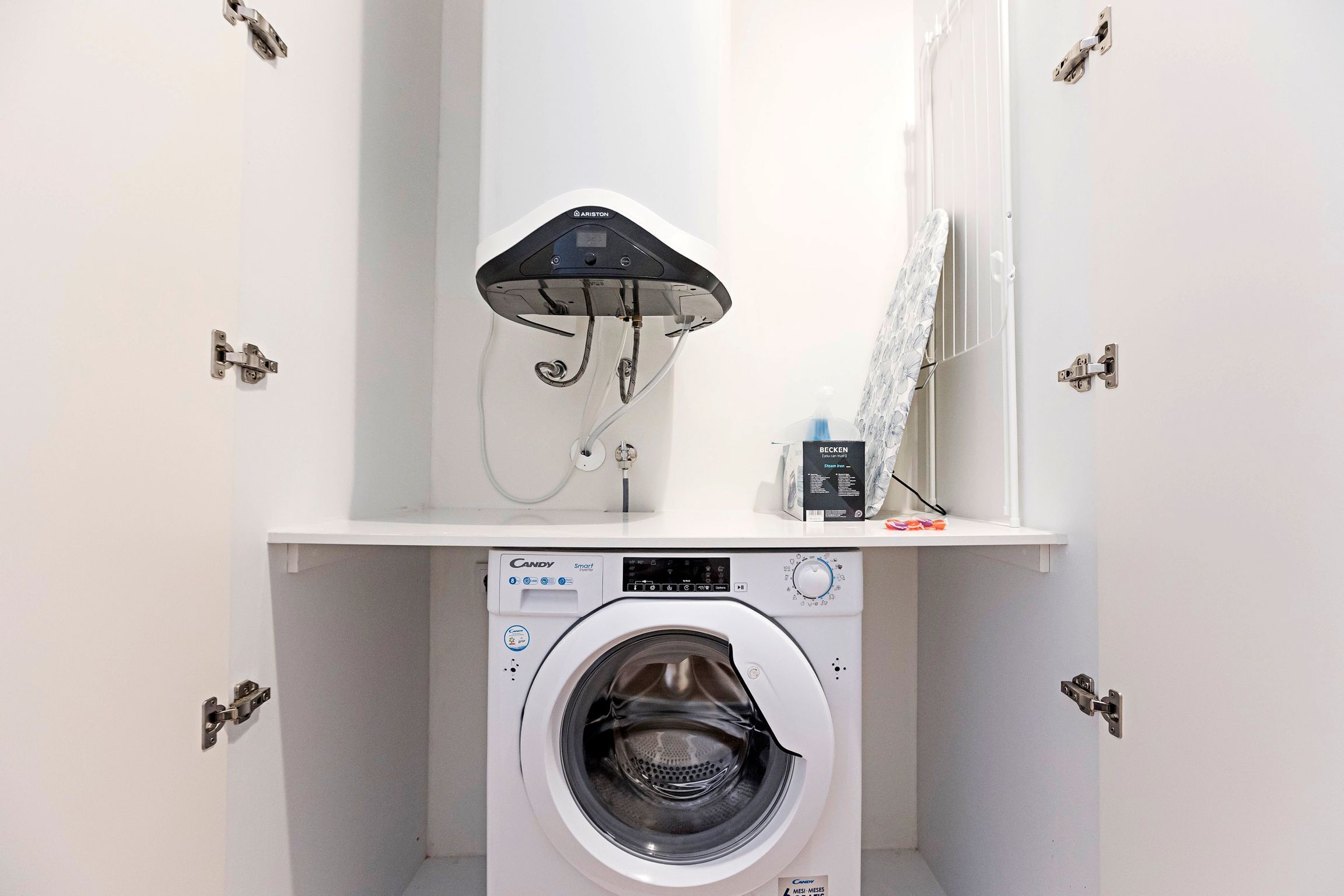A compact laundry area with a Candy Smart washing machine and a wall-mounted dryer.