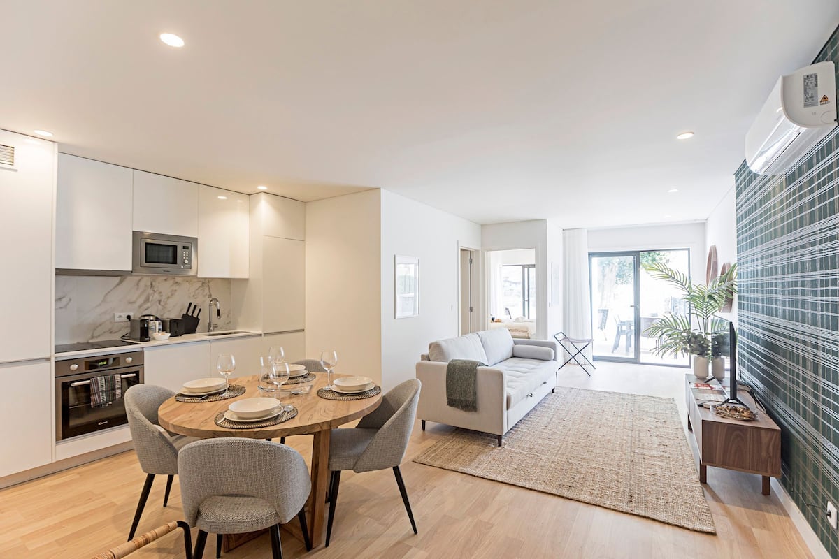 A modern kitchen with a microwave, stove, and dining area with chairs and a table set for two.