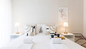 A hotel room with a neatly made bed, two bedside tables with lamps, a framed artwork on the wall, and a chair. - Rua do Paraíso (Porto)