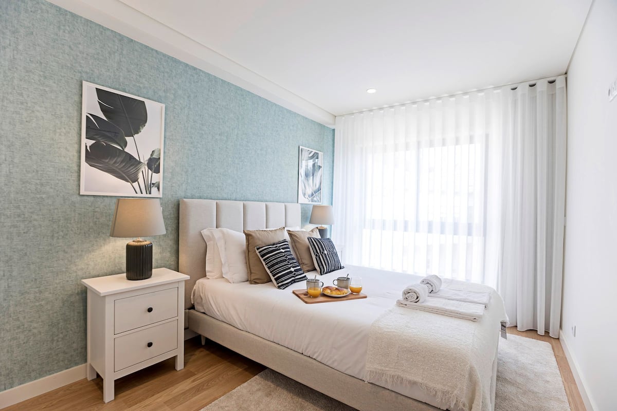A neatly arranged bedroom with a bed, bedside tables, and artwork on the walls.