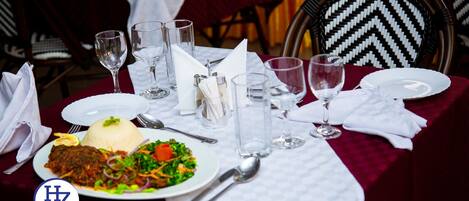 A dining table set with a plate of food, glasses, and cutlery.
