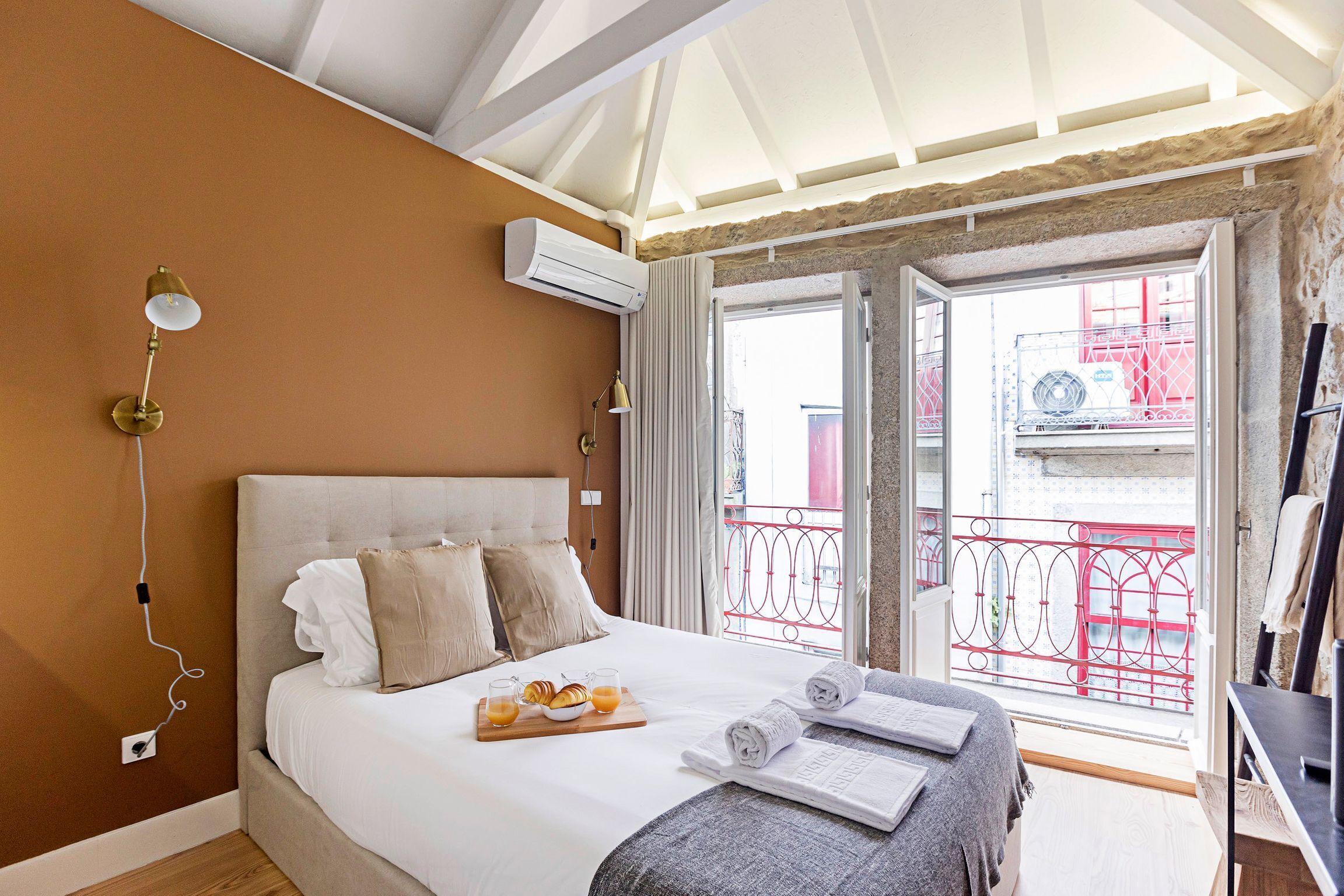Habitación de hotel con cama, bandeja de desayuno, toallas y un equipo de aire acondicionado.