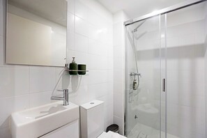 A modern bathroom with a glass-enclosed shower, a white sink, and a mirror.