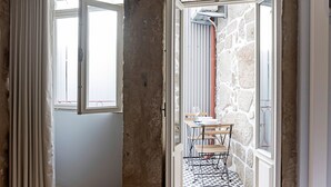 A room with a stone wall, a window with curtains, and a table with chairs. - Cimo de Vila 62 by LovelyStay (Porto)